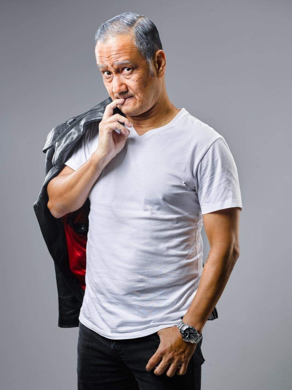 Singapore advertising portrait photography: publicity portrait. Gurmit Singh in a white T-shirt with a jacket over his shoulder and a hand on his chin, studio portrait for Sing'Theatre's Forever Young (2021)