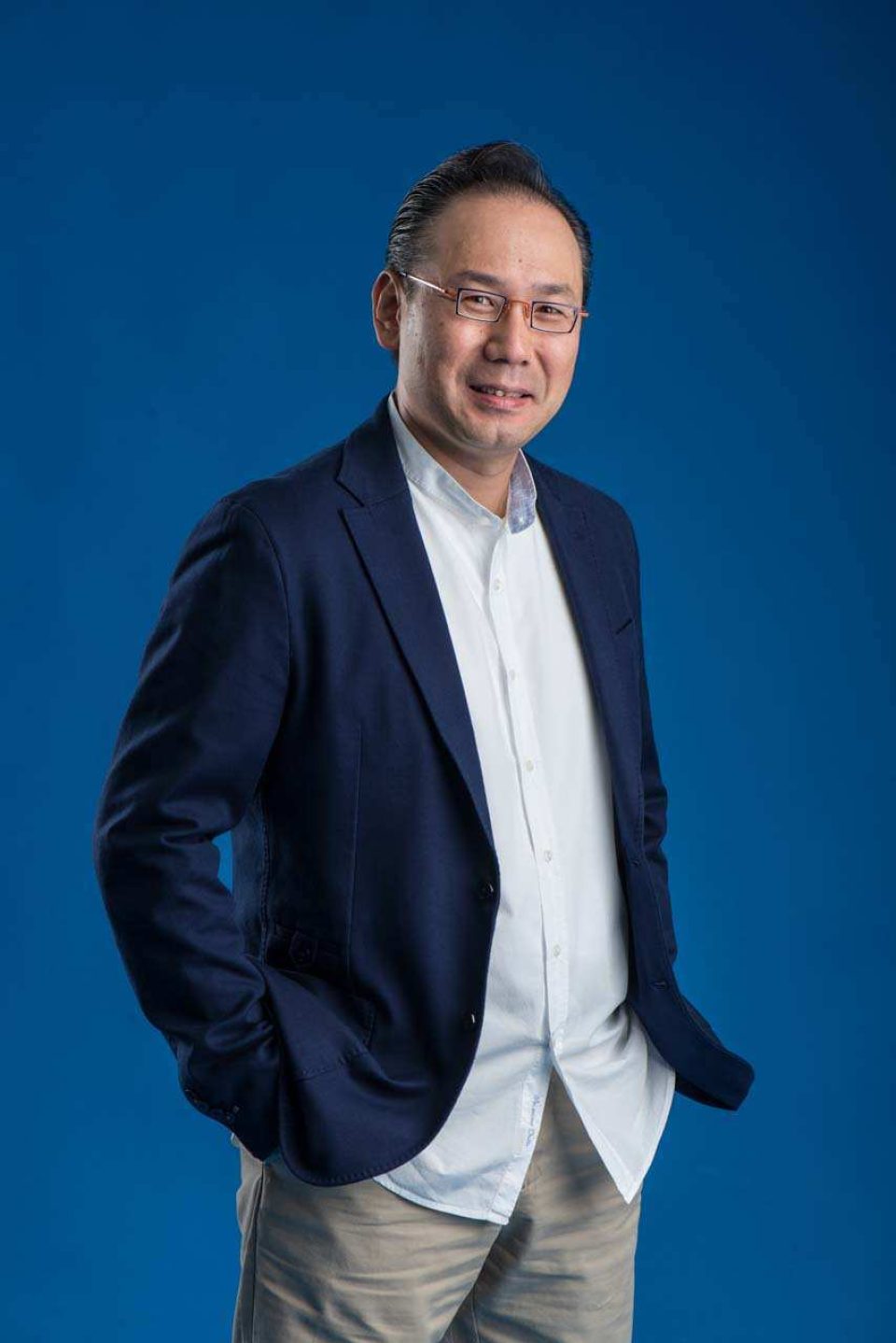 In this series of studio portrait photography, these contrasting portrait styles in the images above. The first image exudes a more classic, formal approach, presenting a professional yet approachable stance. The second image, however, is more relaxed, casual, and warm