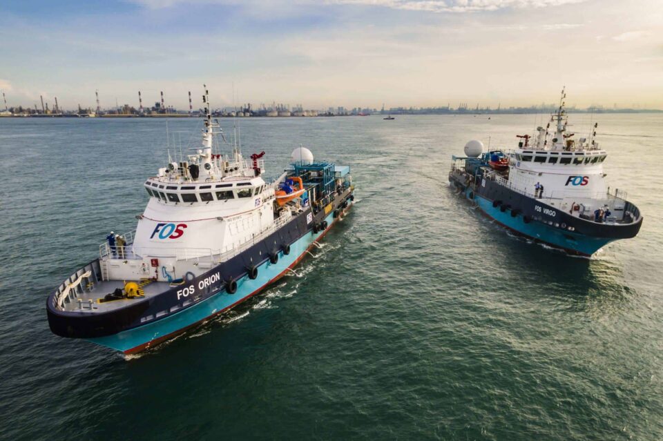 Aerial view of two harbour tugs working side by side against the Singapore port skyline — Singapore industrial photography, port operations, aerial maritime photography