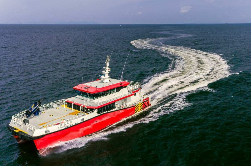 Aerial photograph of the first Brevity class catamaran carving a curved wake at speed — Singapore industrial photography, marine aerial, marine drone photography