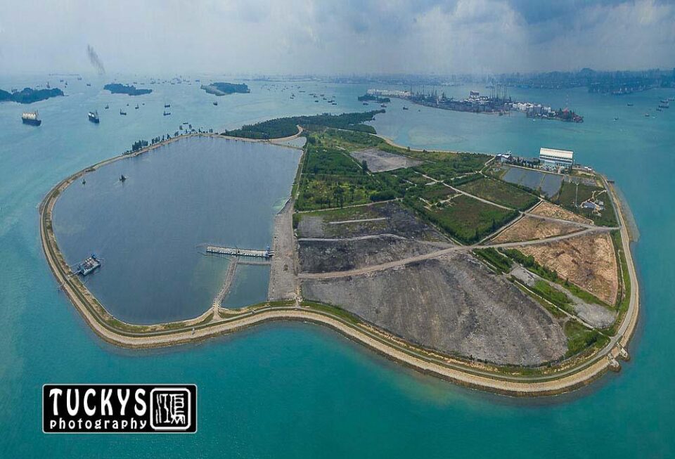 Semakau Landfill whole from the air: reclaimed cells, bund and lagoon in one frame — aerial drone photography Singapore