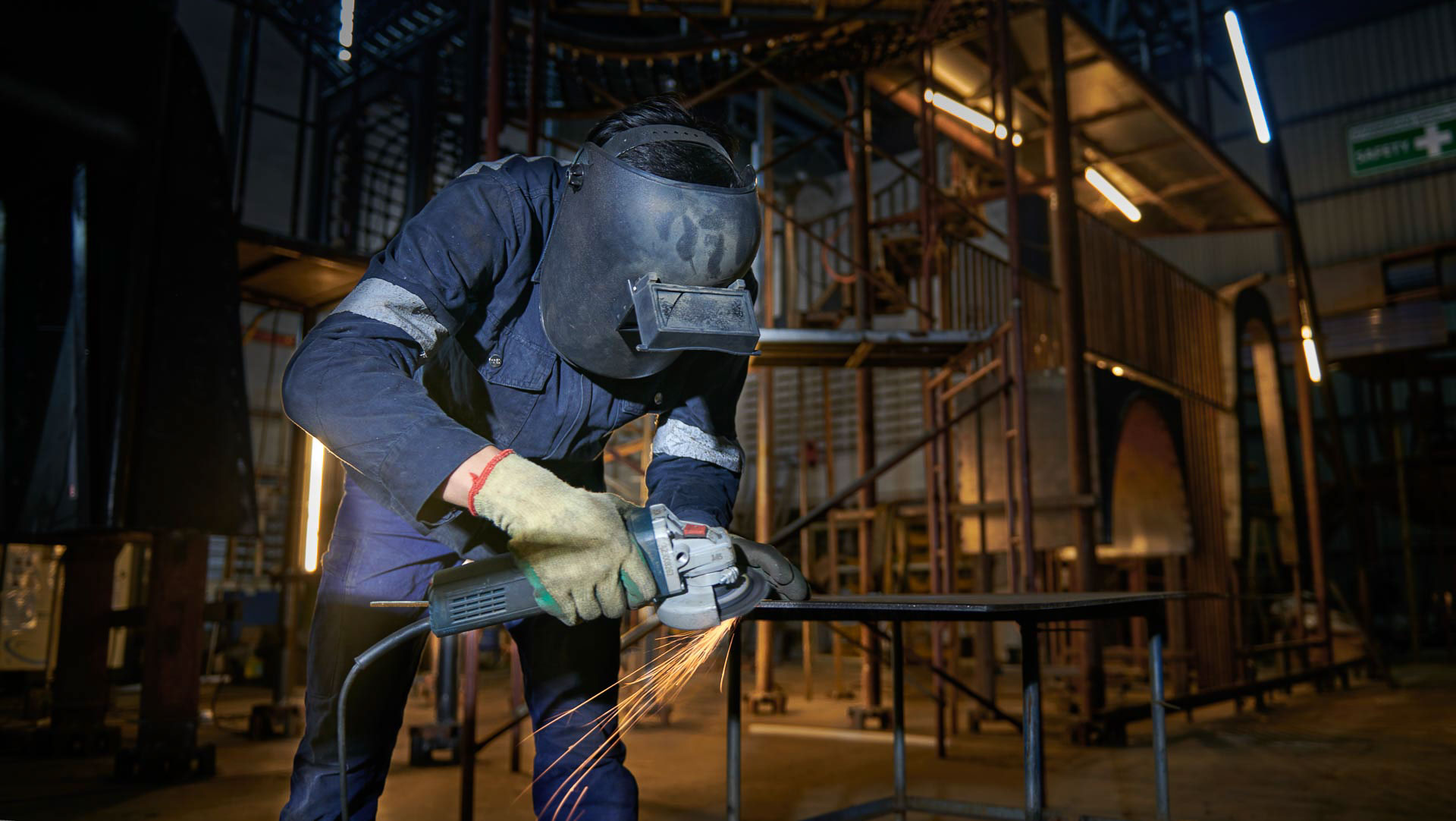 Welder in a face shield grinding a steel joint as sparks fly, Singapore welding photography by Tuckys Photography