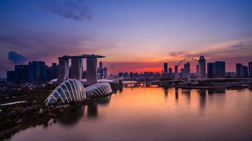 Marina Bay at sunset with the Gardens by the Bay domes and Marina Bay Sands in silhouette against the afterglow — aerial photography Singapore