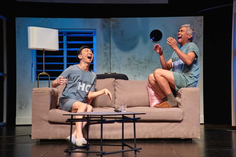 Singapore theatre photography: stage photography. Hossan Leong and Rody Vera laughing on a sofa, one with his head thrown back, in Old Gaze